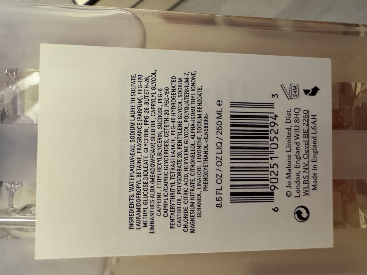 瓶身背標。INGREDIENTS 全成分、8.5 FL OZ / OZ LIQ / 250 ML e、條碼 690251052943、© Jo Malone Limited, Dist. London, England W1U 8HQ／WLBS NV, Oevel BE-2260／Made in England L6AH、開蓋圖示 24M。